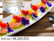 Ceviche from red trout on plate with cumquat, kiwi, figs and flower. Стоковое фото, фотограф Яков Филимонов / Фотобанк Лори