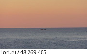 Вечерний закат на Охотском море. Лодка с рыбаками, перед ней выглядывают из воды ларги (пестрые нерпы) Стоковое видео, видеограф Роман Аксёнов / Фотобанк Лори