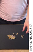 A woman unpacking jewelry, taking out a gold-colored necklace, bracelet, earrings, and ring from small bags. Vertical video. Стоковое видео, видеограф Vadzim Yakubovich / Фотобанк Лори