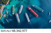 Azure Anchorage: A fleet of merchant vessel at rest in translucent turquoise harbor waters, overhead view, coastal proximity. Стоковое AI-изображение, AI-художник Данила Большаков / Фотобанк Лори