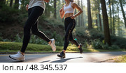Close-up of legs of the couple running in the forest trail. Intentional motion blur. The focus is on feet. Стоковое AI-изображение, AI-художник Катерина Ковалева / Фотобанк Лори