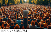 A massive audience assembles in a park for an outdoor speech, with a microphone in the foreground highlighting the gathering's energy and enthusiasm. Стоковое AI-изображение, AI-художник Данила Большаков / Фотобанк Лори
