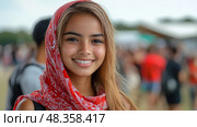 A cheerful young woman with a radiant smile poses confidently at a festival, wearing a red scarf, with lively festival-goers in the background. Стоковое AI-изображение, AI-художник Данила Большаков / Фотобанк Лори