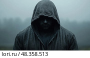 A person wearing a dark hooded garment stands still in a misty environment, evoking a sense of enigma and solitude at dawn. Стоковое AI-изображение, AI-художник Данила Большаков / Фотобанк Лори
