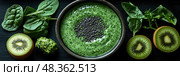 A vibrant green smoothie bowl sits in a dark dish, surrounded by fresh spinach leaves and sliced kiwi, featuring a sprinkle of seeds on top. Стоковое AI-изображение, AI-художник Данила Большаков / Фотобанк Лори