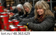 Dedicated volunteers work together in a community center to prepare food packages for local families facing hardship during winter. Стоковое AI-изображение, AI-художник Данила Большаков / Фотобанк Лори
