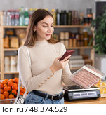 Girl scan QR-code on raw pork sausages in store. Стоковое фото, фотограф Яков Филимонов / Фотобанк Лори