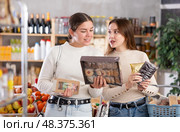 Two girls in store while shopping, choose sweets and chat sweetly. Стоковое фото, фотограф Яков Филимонов / Фотобанк Лори