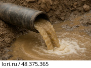 Сточная труба. Грязная вода вытекает из трубы на земляную поверхность. Стоковое AI-изображение, AI-художник Башкирова Анна / Фотобанк Лори