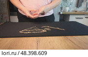 A woman reviewing jewelry, laying out a gold-colored necklace, bracelet, earrings, and ring on a table. Стоковое видео, видеограф Vadzim Yakubovich / Фотобанк Лори