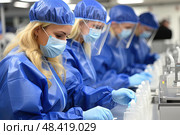 Group of women, wearing blue lab coats and masks, engage in groundbreaking scientific research with utmost precision and creativity. Стоковое AI-изображение, AI-художник Данила Большаков / Фотобанк Лори