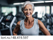 Radiant Joy: Gym-Goers Exuberance Blossoms in the Golden Years. Older woman exudes happiness as she smiles while exercising in vibrant gym, showcasing the beauty of embracing fitness at any age. Стоковое AI-изображение, AI-художник Данила Большаков / Фотобанк Лори