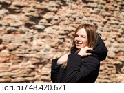 Smiling Woman Enjoys a Sunny Day Outdoors in a Charming Historical Setting With Rustic Walls. Стоковое фото, фотограф Aleksandr Golubev / Фотобанк Лори