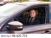 Smiling Woman Shares Joy While Driving in Her Sleek Modern Car on a Sunny Afternoon. Стоковое фото, фотограф Aleksandr Golubev / Фотобанк Лори