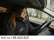 Driving Through a Serene Cityscape With a Confident and Focused Woman at the Wheel. Стоковое фото, фотограф Aleksandr Golubev / Фотобанк Лори