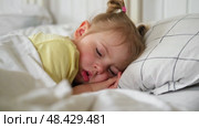 Peaceful adorable baby sleeping on a bed at home. Slumbering little child. Two years old girl sleeps peaceful at domestic room interior background. Serene dream. Cute face close up. Deep kid slumber. Стоковое видео, видеограф Марина Демидюк / Фотобанк Лори