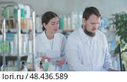 Qualified male and female pharmacists work at a computer, renew stocks in the warehouse, enter new arrivals of medicines and pills. Pharmacists working behind the counter in a pharmacy. Стоковое видео, видеограф Яков Филимонов / Фотобанк Лори