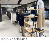 Retail space features neatly organized clothing racks displaying casual apparel and a stylish footwear display. Стоковое фото, фотограф Виктория Тельминова / Фотобанк Лори