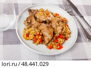 Lunch is served on plate - baked pieces of young rabbit and pearl barley. Стоковое фото, фотограф Яков Филимонов / Фотобанк Лори