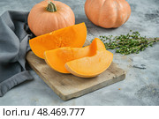 Cutting Fresh Pumpkins on Board. Baked pumpkin. Sliced raw Cucurbita maxima and spices for preparing soup, warm salad, fall dish. Thanksgiving food. Roasted vegetable in olive oil salt pepper, herbs. Стоковое AI-изображение, AI-художник Марина Демидюк / Фотобанк Лори
