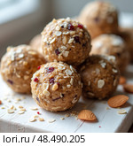 Nutritious energy balls crafted from rolled oats, creamy nut butter, and sweet dried fruits, ideal for fueling a busy day, conveniently prepared in a cozy kitchen setting. Стоковое AI-изображение, AI-художник Ольга Игнашина / Фотобанк Лори