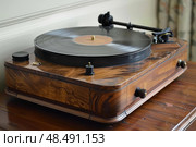 Modern turntable playing vinyl record on wooden table. Стоковое AI-изображение, AI-художник Иван Рябоконь / Фотобанк Лори