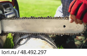 A man saws firewood with a chainsaw in the garden and sharpens a chainsaw chain. Стоковое видео, видеограф Igor Skripachev / Фотобанк Лори