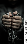 Close-up of hands in chains symbolizing restriction and captivity. Стоковое AI-изображение, AI-художник Olga Didraga / Фотобанк Лори