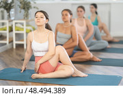 Young girl sitting in twisting asana Matsyendrasana at yoga class. Стоковое фото, фотограф Яков Филимонов / Фотобанк Лори