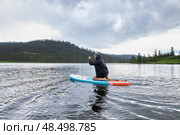 Man paddle boarding on lake in rainy weather and cloudy, overcast sky. Стоковое фото, фотограф Екатерина Якименко / Фотобанк Лори