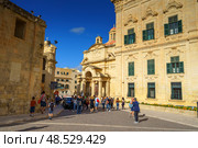 VALLETTA, MALTA - NOVEMBER 12, 2018 - Exterior view of the Auberge de Castille in Castille Square with people walking by. Редакционное фото, фотограф Сергей Богомяко / Фотобанк Лори