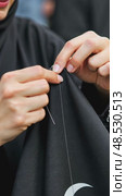 A close-up of a woman's hands sewing a black cloth banner, her fingers trembling slightly as she prepares for the Ashura process. Стоковое AI-видео, аниматор Sergey Grishin / Фотобанк Лори