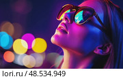 Woman with neon glasses gazes upward, reflecting city lights. The vibrant, futuristic images evoke dreams, hope, and modern glamour. Стоковое AI-видео, аниматор Данила Большаков / Фотобанк Лори