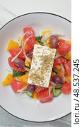 Chef preparing colorful greek salad, featuring fresh tomatoes, cucumber, feta, salmon on crisp white surface. Стоковое видео, видеограф Данил Руденко / Фотобанк Лори