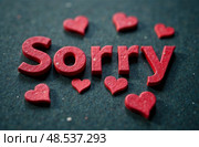 Red letters spelling "Sorry" surrounded by small red hearts on a textured dark background, conveying emotions of apology and affection in a creative and artistic manner. Стоковое AI-изображение, AI-художник Котова / Фотобанк Лори