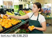 Female seller in apron chooses juicy tangerine. Стоковое фото, фотограф Яков Филимонов / Фотобанк Лори