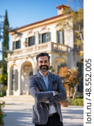 Mature man is standing in front of a grand, imposing house, looking directly at the camera. Стоковое AI-изображение, AI-художник Данила Большаков / Фотобанк Лори