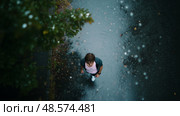 Person walking on a rainy street surrounded by trees during overcast daylight. Стоковое AI-изображение, AI-художник Сергей Толмачёв / Фотобанк Лори