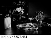 Still life with beads, perfume, lacquered cabinet and glasses, in black and white. Стоковое фото, фотограф Сергей Фролов / Фотобанк Лори