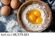 Raw eggs in flour inside wooden bowl, surrounded by scattered ingredients, capturing a rustic baking scene in preparation for homemade cooking. Стоковое AI-изображение, AI-художник Катерина Бондарец / Фотобанк Лори