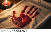 A close-up of a bloodied handprint on a white cloth, symbolizing sacrifice, illuminated by the dim glow of a single oil lamp. Стоковое AI-видео, аниматор Sergey Grishin / Фотобанк Лори