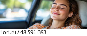 A young woman with curly hair sits comfortably in a car, smiling contentedly with her eyes closed on a bright sunny day. Стоковое AI-изображение, AI-художник Данила Большаков / Фотобанк Лори