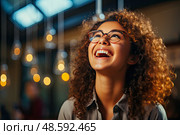 Spirited woman with curly hair and glasses bursts into laughter, radiating infectious joy. Стоковое AI-изображение, AI-художник Данила Большаков / Фотобанк Лори