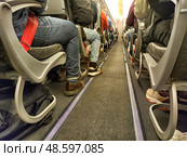 Kazan, Russia - April 03, 2025: Passengers seated in an airplane aisle during a flight to a distant destination. Редакционное фото, фотограф Кривошеина Елена Леонидовна / Фотобанк Лори