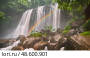 Powerful waterfall cascades down rock face, with vibrant rainbow forming in mist at its center. Стоковое AI-видео, аниматор Данила Большаков / Фотобанк Лори