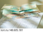 Несколько купюр (российские рубли) лежат на квитанции ЖКХ за квартиру / Several bills (Russian rubles) are lying on the housing and communal services receipt for the apartment. Стоковое фото, фотограф Вячеслав Вольский / Фотобанк Лори