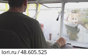 Crane operator loads coal onto barge on the Yenisei River during northern delivery operations. View of the crane operator's hand at work controls the joystick manipulator in the crane cabin rear view, Стоковое видео, видеограф Владимир Разгуляев / Фотобанк Лори