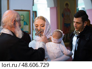 Belarus, Gomel, 25 March. 2018. The Prudhkovsky Church.The baptism of a child.During the baptism of a child, a woman kisses a cross. Редакционное фото, фотограф Лазаренко Светлана / Фотобанк Лори