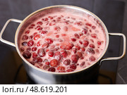 Bubbling red strawberry berries create a vibrant mixture as they simmer in a pot. Стоковое фото, фотограф Виктория Тельминова / Фотобанк Лори