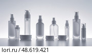 Variety of transparent cosmetic containers arranged on a minimalistic white surface with soft backlighting during early evening. Стоковое AI-изображение, AI-художник Сергей Толмачёв / Фотобанк Лори